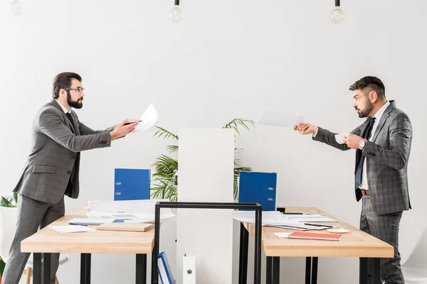 Бізнесмени сваряться в офісі і показують документи один одному — стокове фото