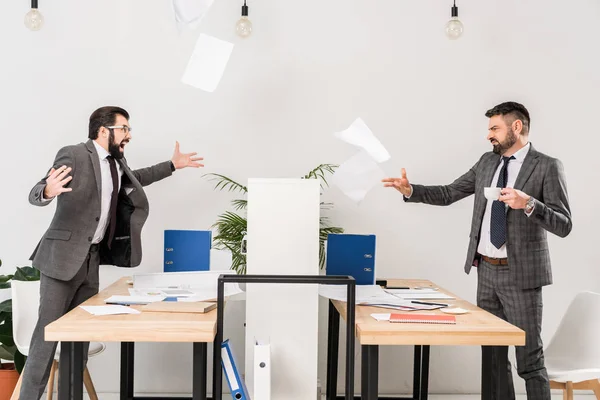 Businessmen quarreling in office and throwing documents — Stock Photo