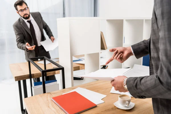 Abgeschnittenes Bild eines Geschäftsmannes, der auf etwas in Dokumenten im Büro zeigt — Stockfoto