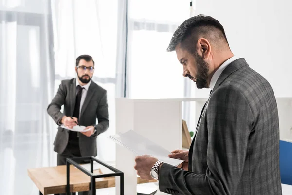 Hombre de negocios guapo mirando los documentos en la oficina - foto de stock