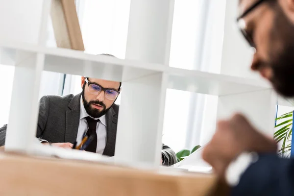 Visión a través de la partición en el hombre de negocios que trabaja en la oficina - foto de stock