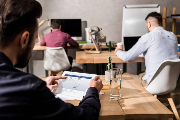 Businessman holding tablet with loaded facebook page — Stock Photo