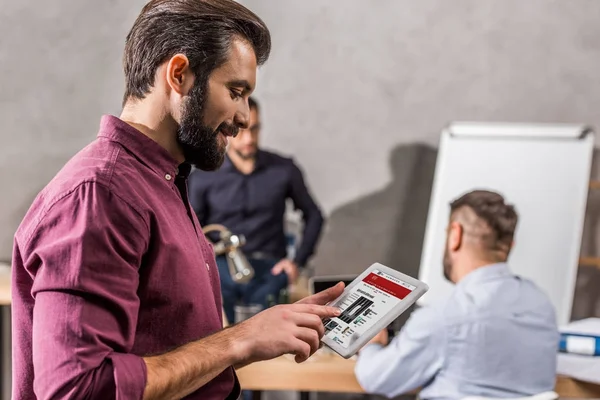 Sonriente hombre de negocios mirando tableta con BBC página de noticias - foto de stock