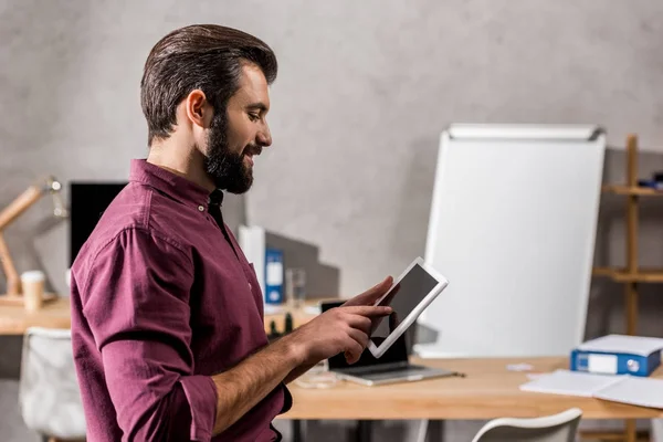 Sonriente hombre de negocios de pie y mirando la tableta - foto de stock