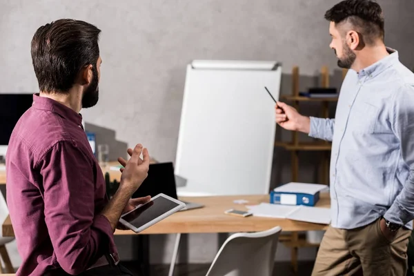 Colleagues talking and looking at flipchart in office — Stock Photo