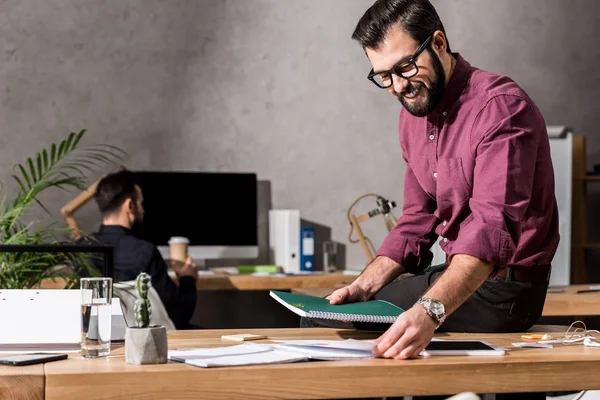 Homem de negócios sorrindo tirar documentos da mesa de trabalho — Fotografia de Stock