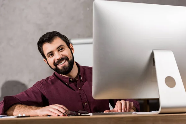 Homem de negócios sorridente sentado no computador no escritório — Fotografia de Stock