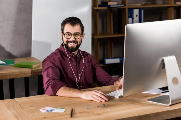 Lächelnder Geschäftsmann, der im Büro am Computer arbeitet und in die Kamera schaut — Stockfoto