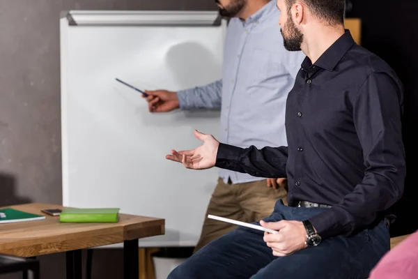 Cropped image of businessmen discussing something near flipchart at work — Stock Photo