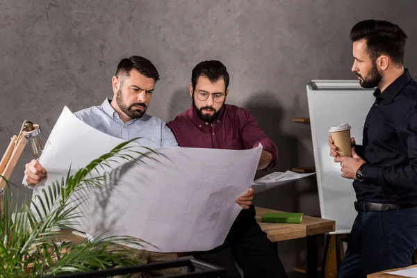 Architects looking at blueprints at working space — Stock Photo