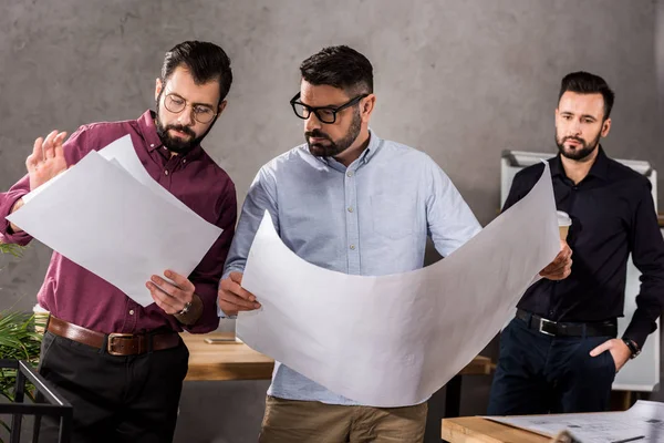 Architects looking at blueprints at working space — Stock Photo