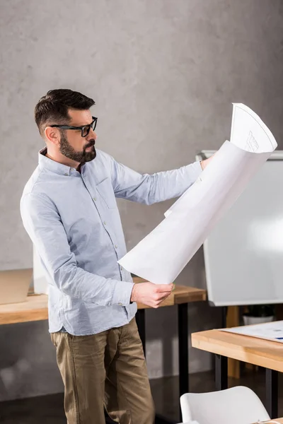 Schöner Architekt schaut sich Bauplan im Büro an — Stockfoto