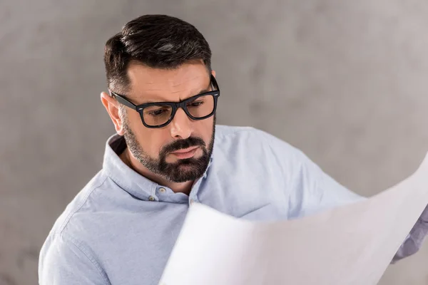 Thoughtful handsome architect looking at blueprint — Stock Photo