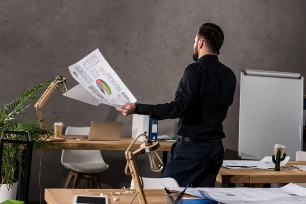 Rear view of architect holding blueprints and talking by smartphone — Stock Photo