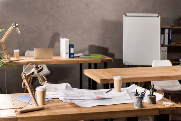 Mesas de trabajo con planos, café y suministros - foto de stock