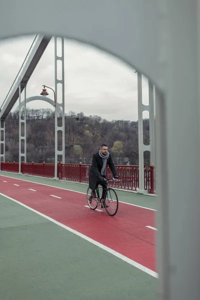 Lonely adult man riding bicycle on pedestrian bridge — Stock Photo