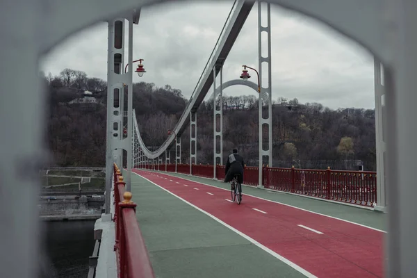 Stylish man riding bicycle on pedestrian bridge — Stock Photo