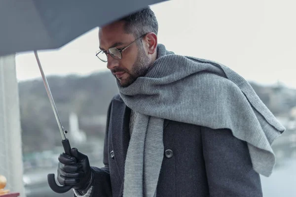 Homem triste solitário em cachecol com guarda-chuva andando sob chuva — Fotografia de Stock