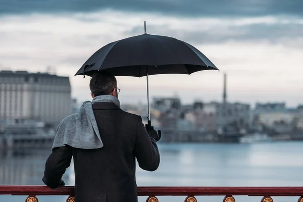 Back view of lonely man with umbrella standing on bridge — Stock Photo