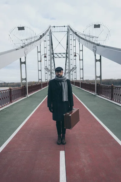 Hombre de mediana edad con estilo con maleta de pie en el puente peatonal - foto de stock