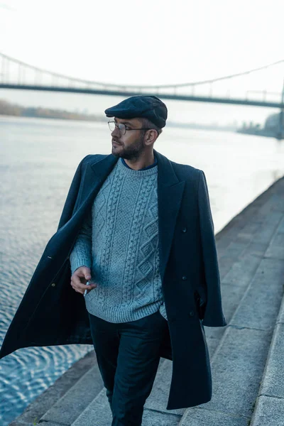 Handsome middle aged man walking by river bank with cigarette in hand — Stock Photo