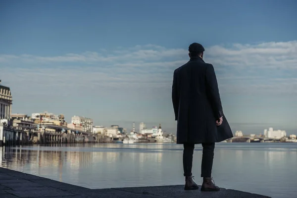 Lonely man standing on river coast and looking away — Stock Photo