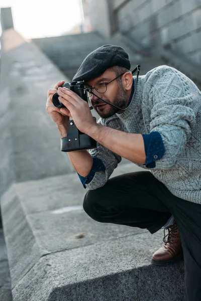 Guapo hombre adulto tomando foto con la cámara de película vintage al aire libre - foto de stock