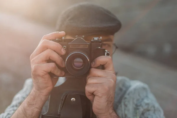 Стильный мужчина фотографируется с винтажной кинокамерой — стоковое фото