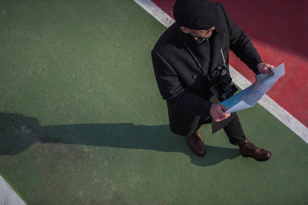 High angle view of traveller in coat and cap walking with map — Stock Photo