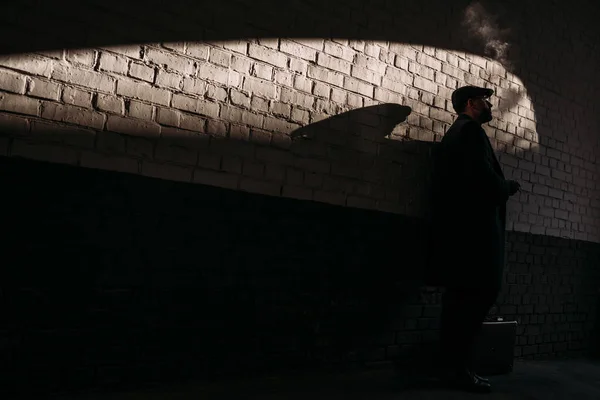 Silhouette dell'uomo che fuma davanti al muro di mattoni — Foto stock