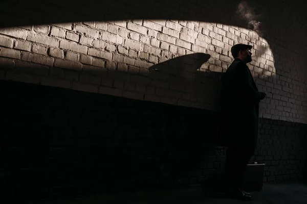 Silhouette of man smoking in front of brick wall — Stock Photo