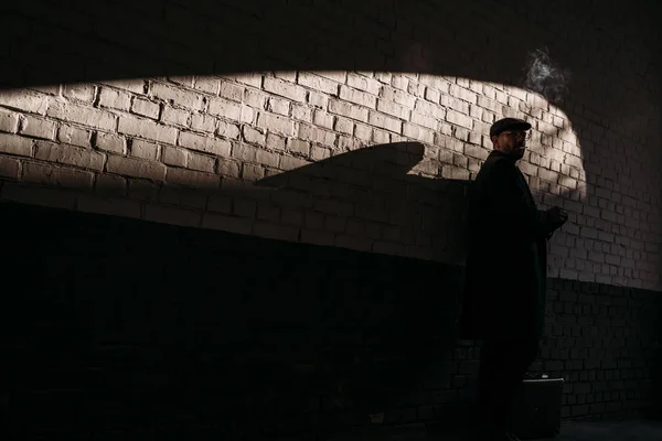 Silhouette de l'homme adulte fumant devant un mur de briques — Photo de stock