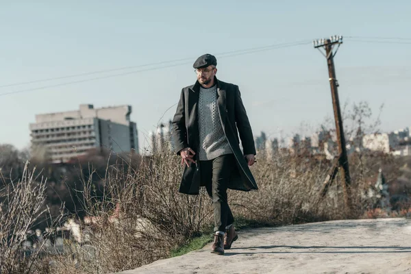 Bel homme d'âge moyen en manteau marchant par la route rurale — Photo de stock