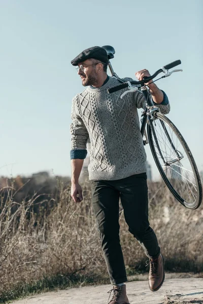 Hombre adulto guapo llevando bicicleta en la carretera rural - foto de stock