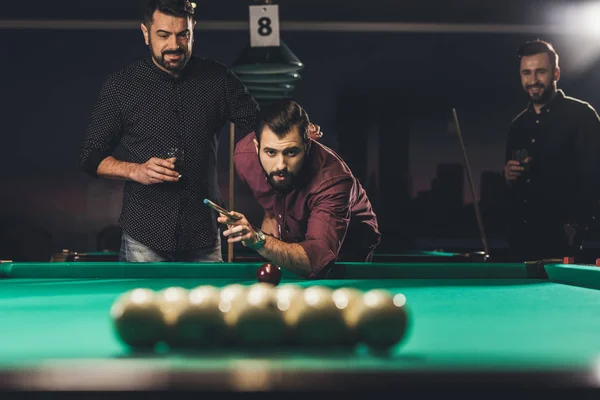 Handsome man playing in pool at bar with friends — Stock Photo