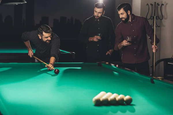 Successful handsome man playing in pool at bar with friends — Stock Photo