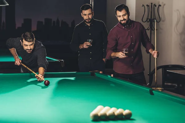 Successful handsome man playing in pool at bar with friends — Stock Photo