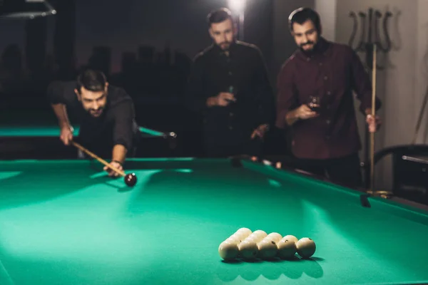 Successful handsome man playing in pool at bar with friends — Stock Photo