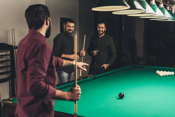 Companhia de homens bem sucedidos ao lado de mesa de bilhar jogo no bar — Fotografia de Stock