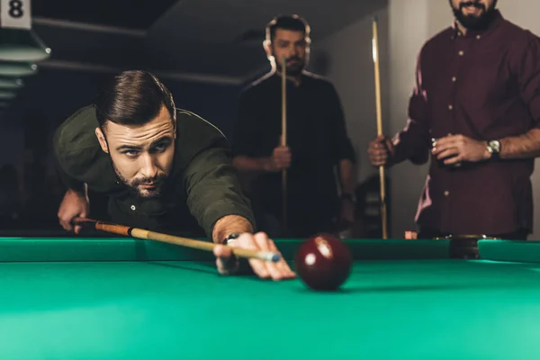 Junger erfolgreicher schöner Mann spielt in russischem Pool an Bar mit Freunden — Stock Photo