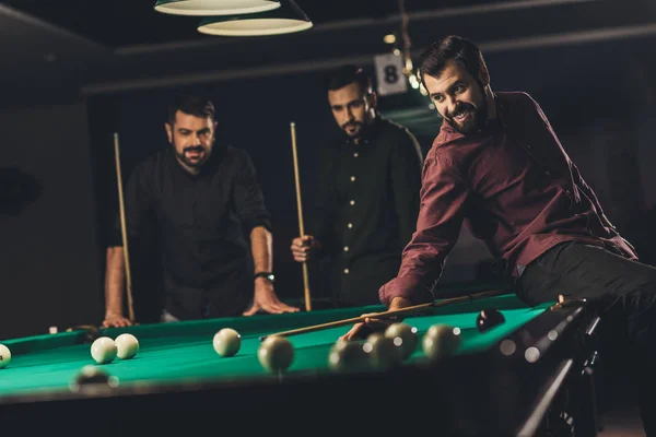 Compañía de jóvenes hombres guapos exitosos jugando en la piscina rusa en el bar - foto de stock