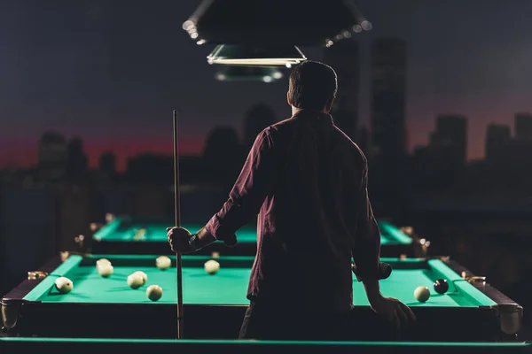 Vue arrière de l'homme réussi debout à côté de la table de billard avec au bar — Photo de stock