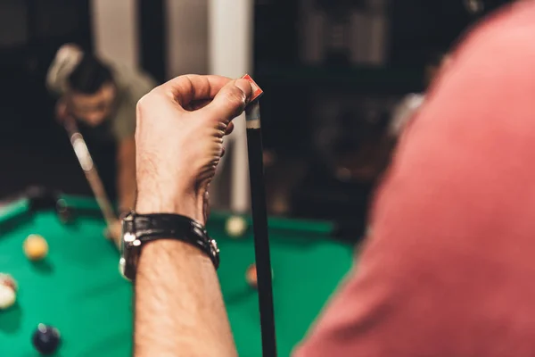 Cropped image of man chalking billiard cue at bar with friends — Stock Photo