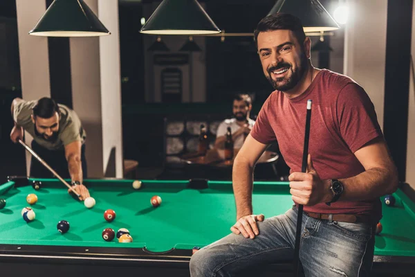 Young handsome caucasian man beside billiard table in bar with friends — Stock Photo