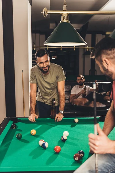 Group of young successful handsome men playing in pool at bar — Stock Photo