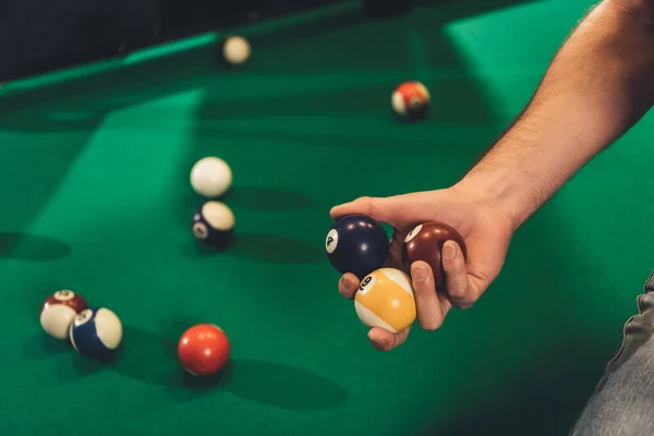 Image recadrée de la main masculine avec des boules de billard à côté de la table de jeu — Photo de stock