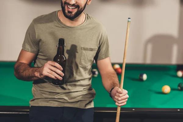 Cropped image of young handsome man drinking beer beside billiard table — Stock Photo