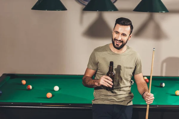 Jeune beau caucasien homme boire de la bière à côté de la table de billard — Photo de stock