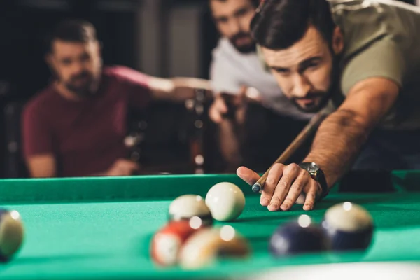 Young handsome man playing in pool with friends at bar — Stock Photo