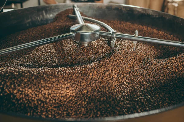 Vista de cerca de granos de café tostado en la máquina - foto de stock